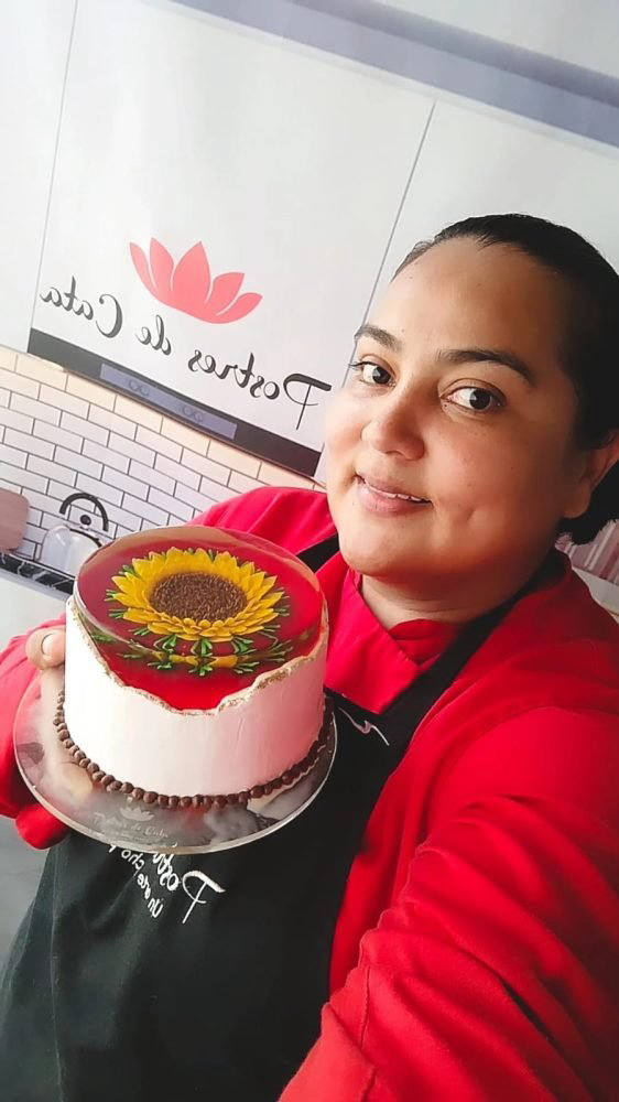 Catalina Bonilla sosteniendo una gelatorta decorada con un girasol